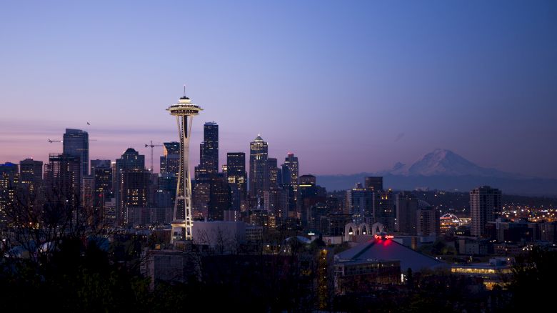 A scenic view of Seattle's skyline at dusk, featuring the Space Needle and Mount Rainier in the background under a twilight sky ending the sentence.